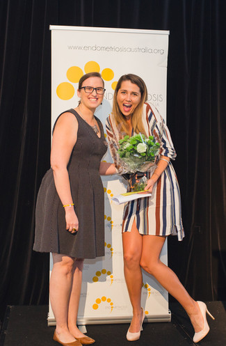 Two Ladies posing with a bouquet of flowers in Endometriosis Australia's Event