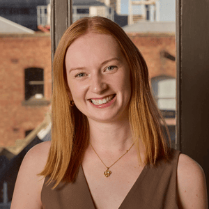 Kara Scott, Endo Australia Champion, smiling at camera. Red-haired woman wearing a brown top against a brick wall background.